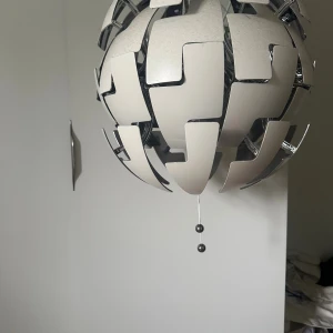 IKEA PS 2014 Taklampa - Modern taklampa från IKEA, modell PS 2014. Sfärisk design med justerbara paneler för att ändra ljusflödet. Vit och kromad finish. i gott skick. Perfekt för vardagsrum, kök eller sovrum.
