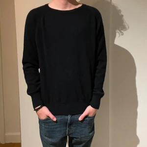 Mörkblå Oscar Jacobson tröja  - Svart, stilren tröja från Oscar Jacobson i mjuk ull. Klassisk rund hals och långärmad modell med ribbade muddar. Perfekt för dig som gillar enkel och clean look med lyxig känsla. Made in Italy.