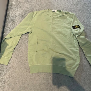 Grön Stone Island sweatshirt - Snygg ljusgrön sweatshirt från Stone Island med klassisk patch på vänster ärm. Tröjan har rund hals, långa ärmar och är gjord i mjuk bomull. Perfekt för dig som vill ha en clean och stilren look med street-vibe.  Priset kan förhandlas. 