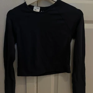 Mörkblå croppad långärmad träningstopp - Säljer en mörkblå croppad långärmad träningstopp från lager 157. Enkel och stilren design med rund halsringning, perfekt att matcha med höga jeans eller leggings. Mjuk och stretchig bomull som sitter skönt mot kroppen. Snygg basic för din garderob!