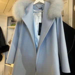 Kappa - Supersnygg ljusblå kappa med stor huva och fluffig pälskant. Kappan har bälte i midjan och långa ärmar, perfekt för att hålla värmen. Stilsäker och elegant look med mjukt material och klassisk passform. Storlek XXS men passar även upp till liten M. Endast testad. Köpt för 5000kr. Pris kan diskuteras!☺️