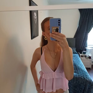 Ljusrosa linnetopp med volang - Supersöt ljusrosa linnetopp med djup v-ringning och volangdetalj. Har bara använt den 2 gånger