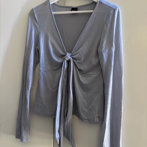 Ljusblå topp Gina Tricot - Ljusblå långärmad topp från Gina Tricot med djup v-ringning och knyt framtill. Super söt topp!