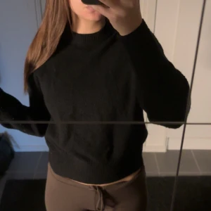 Svart stickad tröja - En enkel och stilren svart stickad tröja med rund halsringning och långa ärmar. Tröjan har en normal passform, lite tjockare vilket är passande till vintern.