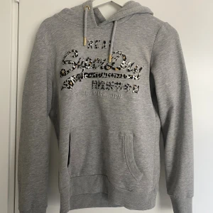 Superdry hoodie - Jättesnygg hoodie från Superdry, använd men i fint skick! Storlek 38, men skulle säga att den sitter ungefär som en xs-s (beroende på hur man vill att den ska sitta) då den är ganska liten i storleken😊. 