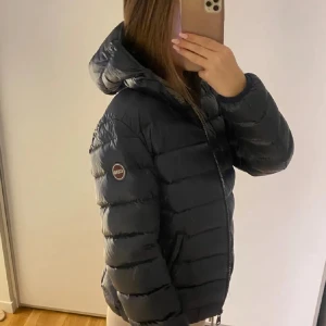 Colmar dunjacka mörkblå - Säljer en snygg och puffig dunjacka från Colmar i mörkblå färg. Jackan har huva, dragkedja framtill och ett  quiltat mönster. Perfekt för dig som vill ha en varm och stilren look under vintern. Logotyp på ärmen och två sidofickor. Köpte för 5000kr