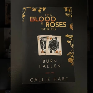 Burn Fallen (The Blood & Roses Series, Book Two) - En snyggt designad bok med spelkort och guldiga rosor på omslaget. Perfekt för dig som gillar spänning och dramatik. Andra delen i en serie som lockar unga vuxna med mystik och intensitet.