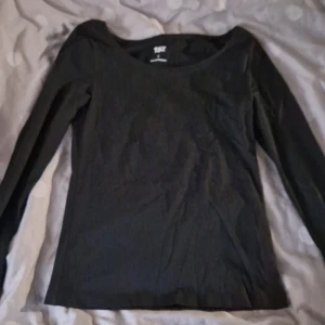 Svart långärmad topp från 157 - Svart långärmad topp från 157 i storlek S. Tillverkad i mjuk bomull med lite stretch för skön passform. Enkel och stilren design med rundad halsringning, perfekt att matcha med jeans eller kjol.