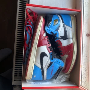 Nike Air Jordan 1 Retro High OG UNC Chicago - Säljer ett par Nike Air Jordan 1 Retro High OG med ikonisk färgblockning i rött, vitt, blått och svart. Skorna har svart swoosh, svarta skosnören och klassisk Jordan Wings-logga på sidan. Ovandelen är i skinn med glansig finish och perforerad tå. Kommer med extra skosnören. Kvitto från plugmeplease kommer med. 