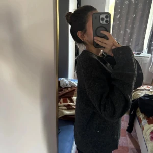 Mörkgrå stickad tröja från H&M - Mysig mörkgrå stickad tröja från H&M i storlek XS. Tröjan har en loose passform, rund hals och långa ärmar. Små dekorativa pärlor är utspridda över hela tröjan för en extra touch. Perfekt för kyliga dagar och enkel att matcha med jeans eller mjukisbyxor.