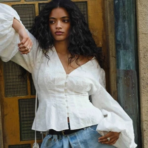 Vit blus med v-ringning och puffärm Adoore  - Superfin vit blus med v-ringning, knappar framtill och breda puffärmar. Blusen har en lätt utsvängd midja och diskret broderat mönster i tyget. Perfekt att styla med jeans för en trendig look. Aldrig använd💓