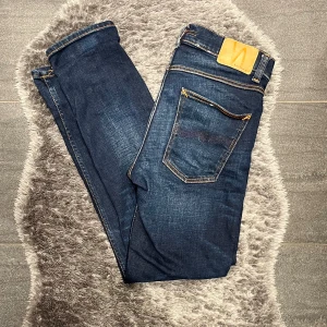 Nudie Jeans Lean Dean Mörblåa  - Klassiska mörkblå jeans från Nudie Jeans i modellen Lean Dean. Slim fit med modern passform. Mycket fint skick och redo för många fler användningar.  Storlek: W31 L30 || || Färg: Mörkblå ||Modell: Lean Dean ||Skick: Mycket fint skick
