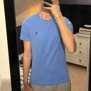 Blå t-shirt från Polo Ralph Lauren - Snygg blå t-shirt från Polo Ralph Lauren med klassisk passform och broderad logga på bröstet 