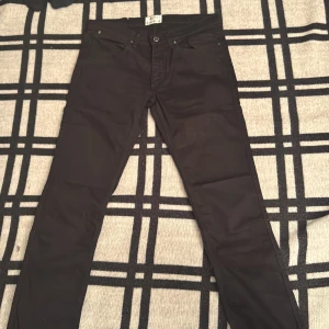 Svarta jeans från Acne Studios - Snygga svarta jeans från Acne Studios med klassisk femficksdesign och silverfärgade nitar. Modellen har rak passform och normal midja, tillverkade i slitstarkt bomullstyg. Perfekt för dig som gillar stilrena och tidlösa plagg.