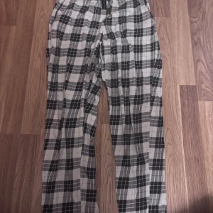 Rutiga byxor från Kappahl, storlek S - Snygga och bekväma byxor från Kappahl i svartvitt rutigt mönster. Byxorna har resår i midjan och är tillverkade i ett mjukt och lätt material, perfekta för en chill och avslappnad stil.