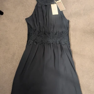 Mörkblå klänning från Vila - Supersnygg mörkblå klänning från Vila med vackert spetsband i midjan. 