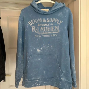 Blå hoodie från Denim & Supply R. Lauren - Säljer en blå hoodie från Denim & Supply R. Lauren med tryck på bröstet och coolt blekt mönster. Tröjan har huva, magficka och långa ärmar. Tveka inte på att höra av er// pris är inte hugget 