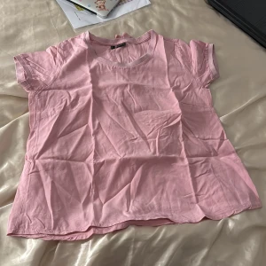 Rosa gullig t shirt  - Rosa t shirt med glitter runt kragen, två rosseter på baksidan av t shirten, stor storlek men liten passform, passar M/L/XL