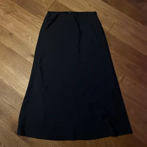 Svart långkjol från Gina Tricot - En stilren svart långkjol från Gina Tricot i storlek S. Kjolen har en rak och enkel design med resår i midjan för en bekväm passform. 