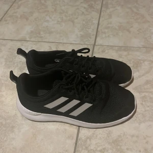 Svarta Adidas sneakers - Svarta Adidas sneakers med vita ränder, endast använda inomhus en gång. 