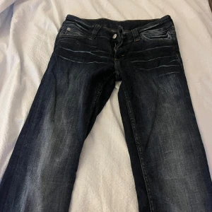 Cheap Monday Booty byxor mörkblå jeans - Mörkblå jeans från Cheap Monday, modell Booty, med klassisk femficksdesign och snygga slitningar framtill. Jeansen har raka ben och normal passform, med coola detaljer som märkets ikoniska dödskallepatch bak och rosa logga på insidan.