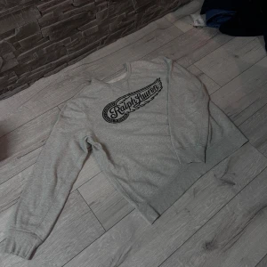 Grå sweatshirt Ralph Lauren  - Snygg grå sweatshirt från Ralph Lauren Denim & Supply i storlek XL. Tröjan har ett stort svart tryck med logga på bröstet och klassisk rund hals. Mjuk bomullskvalitet och långa ärmar med ribbade muddar för extra komfort. Xl man inte barn storlek 