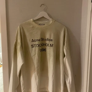 Vit långärmad tröja Acne Studios - Vit långärmad tröja från Acne Studios med tryck 'Acne Studios STOCKHOLM 1996' på bröstet. Tröjan har en klassisk rund halsringning och är gjord i mjuk bomull. Perfekt för en clean och stilren look.