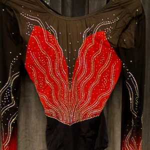 Svart och röd glittrig långärmad gymnastikdräkt  - Säljer en sjuk snygg långärmad gymnastikdräkt från Milano i svart och rött med glittrande paljetter och vågiga mönster. Dräkten har mesh och på armarna. Perfekt för dig som vill sticka ut på träning eller tävling!🌸helt ny, aldrig använd med lappen fortfarande på. Jag har kvar påsen den kom i!