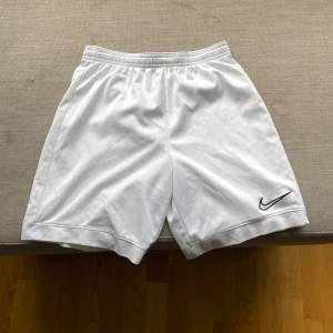 Säljer ett par vita träningsshorts från Nike i storlek L. De är gjorda av polyester och har en elastisk midja för en bekväm passform. Shortsen har en liten Nike-logga på ena benet. De är i bra skick men har några små fläckar.