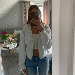 Vit croppad hoodie från BikBok - Säljer en vit croppad hoodie från BikBok. Den har en dragkedja framtill och långa ärmar. Använd några gånger men i bra skick. hör av dig för fler bilder💕