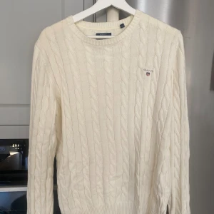 Offwhite kabelstickad GANT  - Säljer en stilren och snygg kabelstickad tröja från GANT i offwhite/krämvit. Tröjan är i fint skick och har bra passform. Perfekt för höst, vinter och vår!