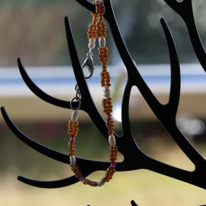 Färgglatt pärlarmband med vita detaljer - Säljer ett superfint armband med små färgglada pärlor och vita detaljer. Armbandet har en enkel men snygg design med en liten karbinhake som lås. Perfekt för att liva upp vilken outfit som helst! 💛