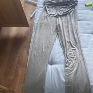 Säljer en snygg beige jumpsuit. Den är gjord av ett mjukt och bekvämt material, perfekt för både vardag och fest. Jumpsuiten har en tight passform upptill och vida ben, vilket ger en stilren och modern look. Perfekt för sommarens alla tillfällen!