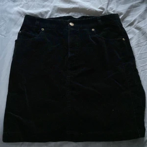 Svart manchesterkjol från 365 Sunshine - Säljer en snygg svart manchesterkjol från 365 Sunshine. Kjolen är i storlek 36 och har en klassisk design med knäppning fram. Perfekt för höst och vinter, och kan stylas både upp och ner beroende på tillfälle. Den är i bra skick och redo för en ny ägare!