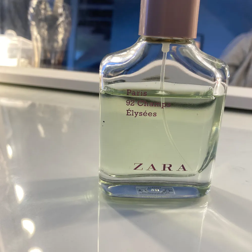 Säljer en elegant parfym från Zara med namnet Paris 92 Champs Élysées. Flaskan är genomskinlig med en ljusrosa kork och rymmer 60 ml. Parfymen har en fräsch och sofistikerad doft, perfekt för både vardag och speciella tillfällen. Flaskan har en stilren design med rosa text på framsidan. Köp direkt eller ge prisförslag 💛. Parfym.