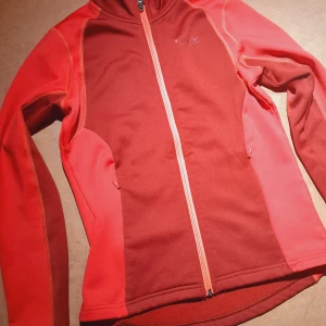 Röd fleecejacka från Everest - Röd fleecejacka från Everest i storlek S. Nyanserna är ljusröd, hallonröd och dragkedjan är neonorange (snyggt!). Fickor med dragkedja. Passar både till vardags och träning. Fint skick!