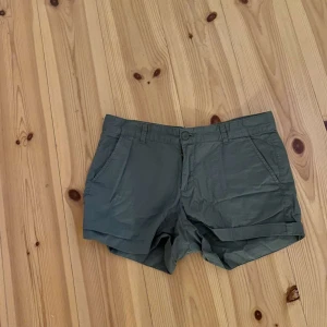 Gröna shorts från Etirel - Säljer ett par gröna shorts från Etirel i storlek 38. De är perfekta för sommaren med sin bekväma passform och stilrena design. Shortsen har en knapp och dragkedja framtill samt fickor på sidan.