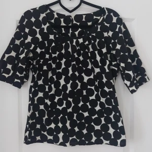 Svartvit prickig blus - Säljer en snygg svartvit blus med stora prickar. Blusen har trekvartsärmar och en rund halsringning. Perfekt för både vardag och fest!