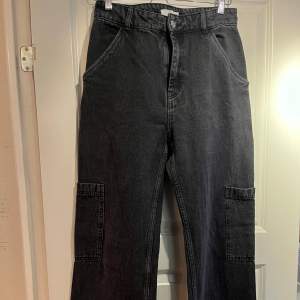 Säljer ett par svarta jeans från H&M i storlek EUR 38. Byxorna har en hög midja och är tillverkade i ett slitstarkt material. De har flera praktiska fickor och en avslappnad passform. Perfekta för en cool och bekväm stil!