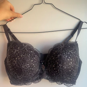 Svart spets-bh från Stella M - Säljer en elegant svart spets-bh från Stella M i storlek 75D. Bh:n har justerbara axelband och en vacker spetsdesign med en liten rosett i mitten. Perfekt för festliga tillfällen eller när du vill känna dig extra fin. Köp direkt eller ge prisförslag 💛