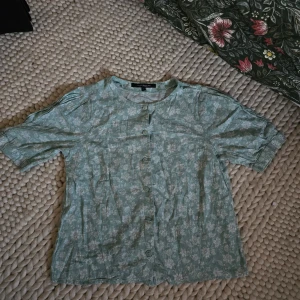 Blommig kortärmad blus  - Ljusblå kortärmad blus med blommönster! Super härlig! Materialet är ganska tunnt så perfekt till sommaren. Den är från KappAhl och passar som en M/L! Pris kan förhandlas 