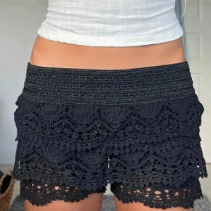 Svarta spetsshorts med volanger - Säljer superfina svarta spetsshorts i storlek XS/S. den är väldigt trendig och eftertraktad!
