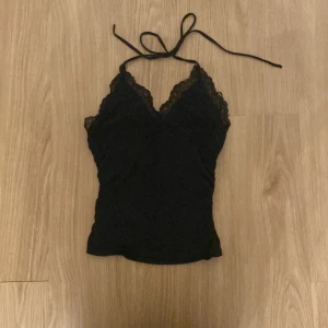 Svart spetslinne - Säljer ett svart spetslinne i storlek Xs. Det är ärmlöst och har en vacker spetsdetalj runt halsen och axelbanden. Perfekt för fest eller en utekväll. Linnet är tight och sitter snyggt på kroppen.