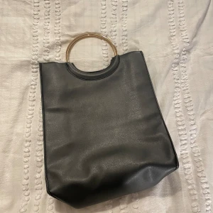 Svart väska - Svart väska med guld handtag, bra för både skolan och jobb, har bra med plats( får plats med en iPad) och använd cirka 5 gånger 