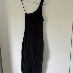 Svart oneshoulder långklänning - Säljer en elegant svart oneshoulder långklänning. Klänningen är i nyskick och har en tight passform 