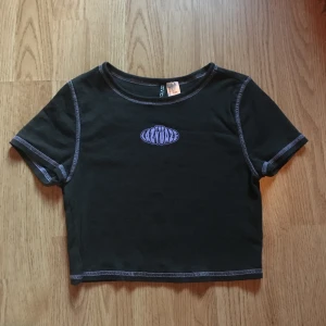 Croptop från H&M - En mörkgrå croptop med lila detaljer från H&M i storlek S