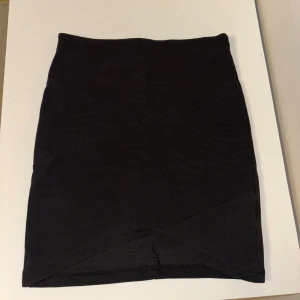Svart ribbad kjol - Snygg svart ribbad kjol i en tight passform. Perfekt för en stilren look. Passar bra på mig som är större än en det som står på lappen.