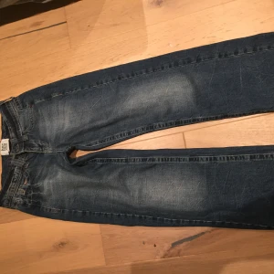 Blå jeans från G-Star - Snygga blå jeans från Urban Outfitters med en klassisk femficksdesign. Jeansen har en lätt tvättad look och är perfekta för en avslappnad stil. De har en knappgylf och är tillverkade i ett slitstarkt denimtyg.