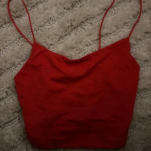 Röd linnetopp från Bershka - Snygg röd linnetopp från Bershka med tunna axelband. Enkel och stilren design som passar till många olika outfits.