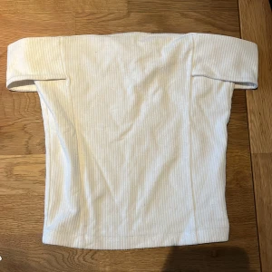 Vit ribbad offshoulder topp från BikBok - Säljer en stilren vit ribbad offshoulder topp från BikBok. Perfekt för en trendig look med sin axelbandslösa design. Toppen är i en mjuk och bekväm kvalitet. Djur finns i hemmet 